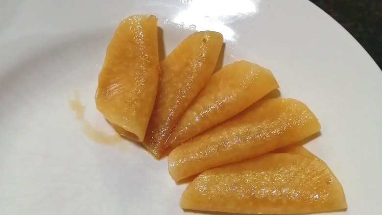 糖醋白萝卜,取一片萝卜片,对折,摆入盘中,每片萝卜与上一片重叠一点
