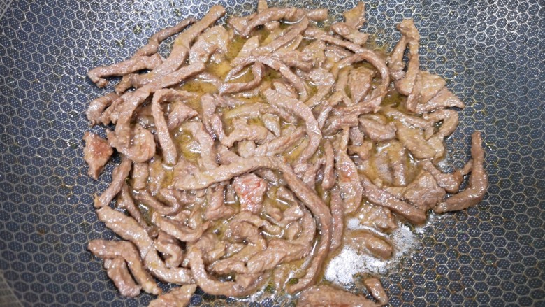 小炒黄牛肉,炒锅内倒适量的食用油烧热,下入腌好的牛肉翻炒至变色,盛出备用。