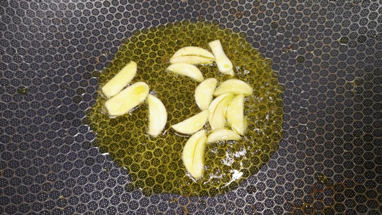 小炒黄牛肉,锅里重新倒油烧热,下入蒜片炒香。