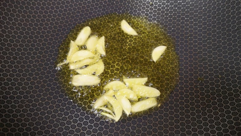 西红柿炒茄子,炒锅内倒适量的食用油烧热,下入蒜片炒香。