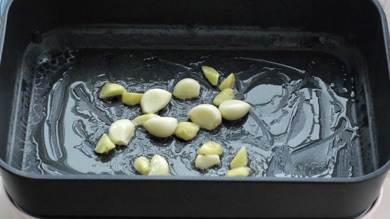 土豆炖鸡翅,在平底锅内倒入适量食用油烧热,把大蒜和姜块放进去,小火炒至大蒜微微泛黄。