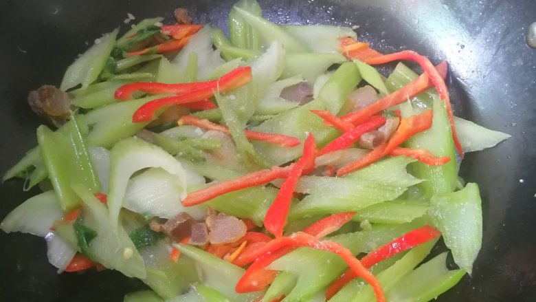 芹菜炒腊肉,炒至辣椒丝断生的时候,加入盐