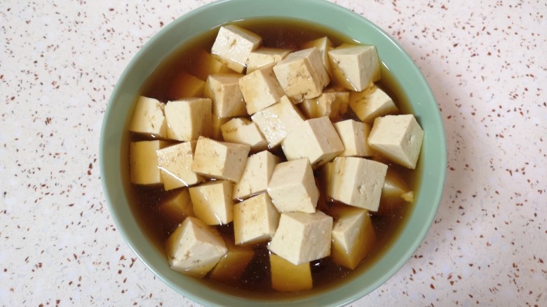 西红柿炒豆腐,将豆腐放入大碗里,放半勺盐和2勺<a style='color:red;display:inline-block;' href='/shicai/ 692'>酱油</a>,加入纯净水浸泡,这样可以去除豆腐的豆腥味,也可以让豆腐入一点底味。