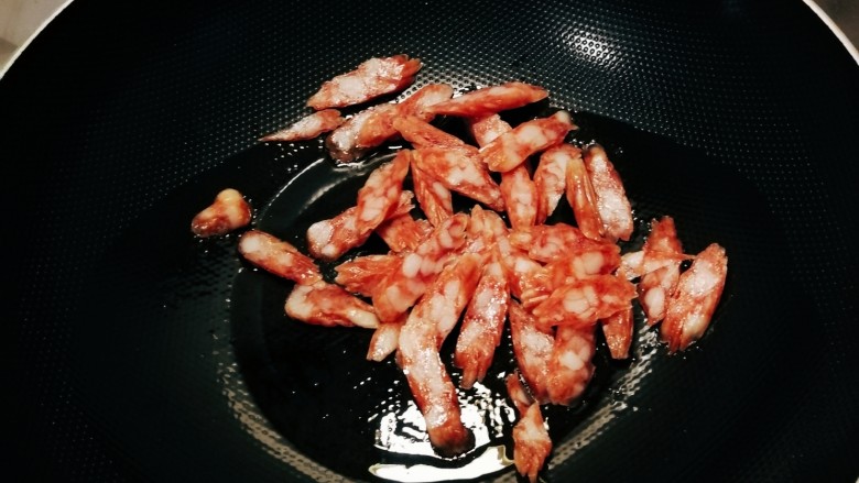 芹菜炒腊肉,起油锅放入食用油,油热后放入腊肉肠翻炒。