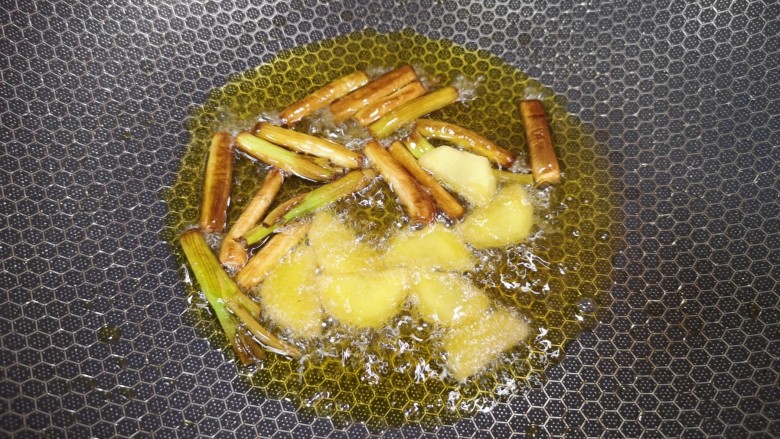 羊肉烩面,中火炸至葱段变成焦黄色,下入生姜片炒香。