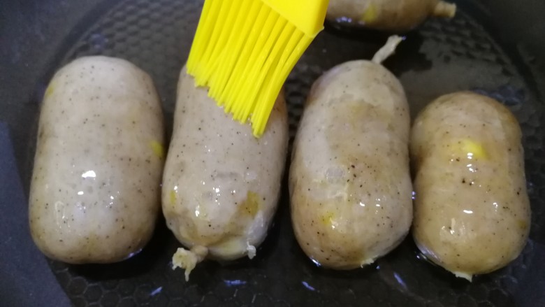 黑胡椒玉米脆皮肠,平底锅倒入适量油,放入玉米肠,表面刷薄油。