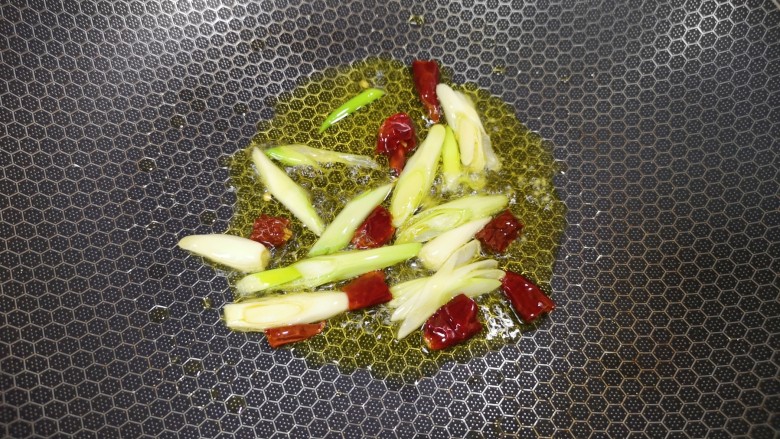 西红柿炒土豆片,炒锅内倒适量的食用油烧热,下入葱段和干红辣椒炒香。