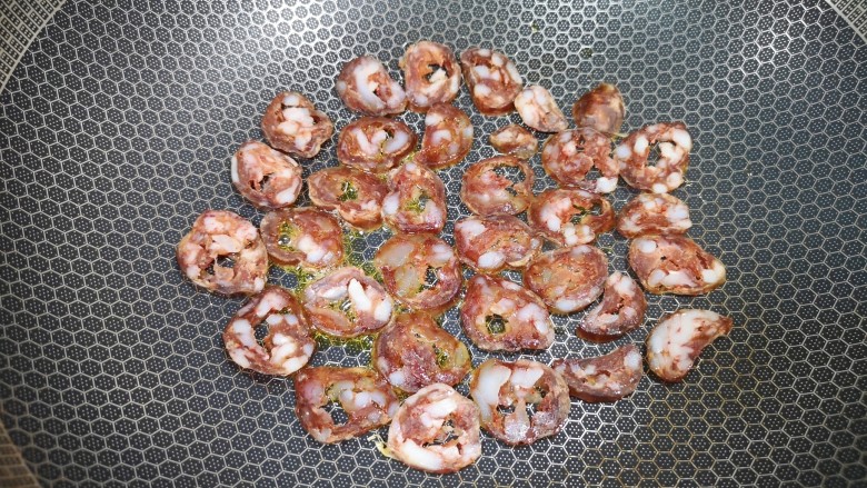 胡萝卜炒腊肉,炒锅内倒少许食用油烧热,码入腊肠片。