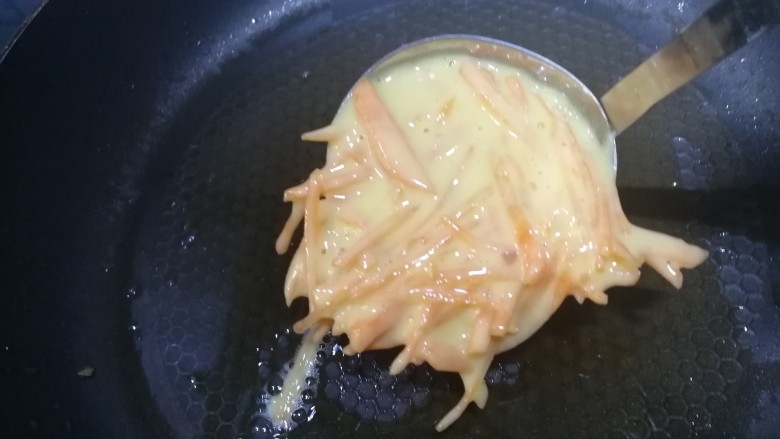 胡萝卜鸡蛋饼,平底锅少油,舀入胡萝卜丝鸡蛋面糊。