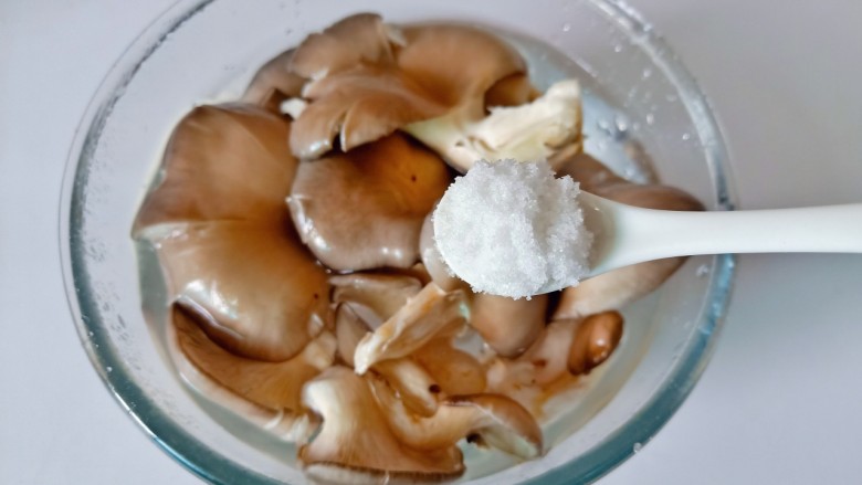 青椒炒平菇,加一勺食用盐浸泡一下,再用清水冲洗干净。