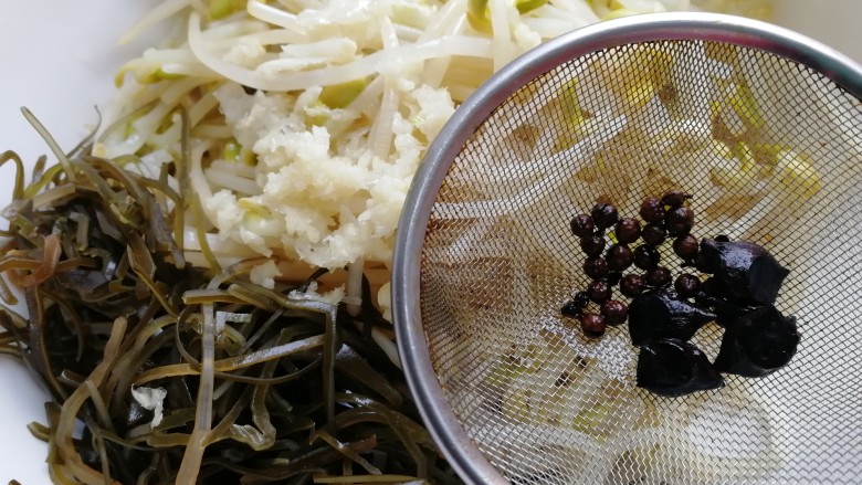 黄豆芽拌海带,热油浇到蒜泥上,纱网滤去花椒,八角。