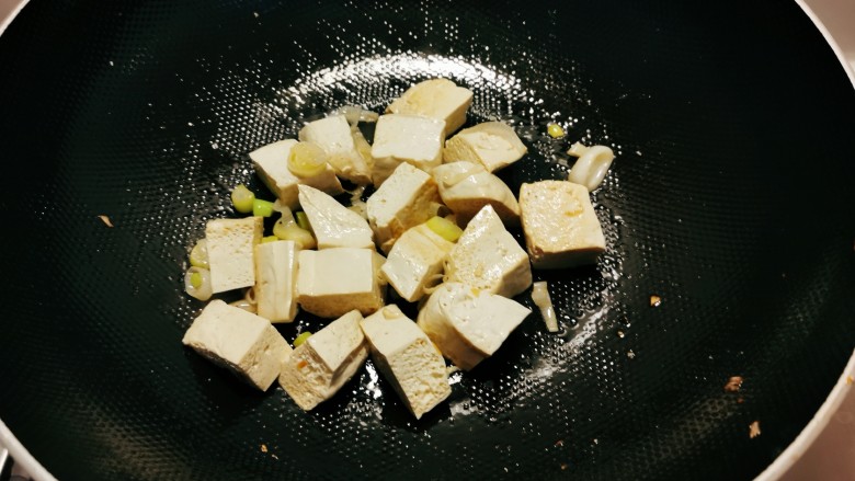 榨菜豆腐汤,再起油锅放入1汤匙食用油,放入葱片炒香,放入豆腐翻炒。
