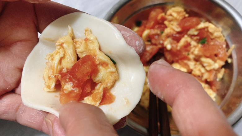 西红柿鸡蛋饺子,食指蘸适量水,在饺子皮外圈,然后捏紧饺子。