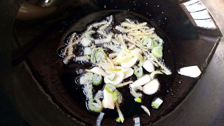 尖椒肉丝,锅中适量油烧至7成热,放入葱花,蒜瓣和姜丝爆出香味儿。