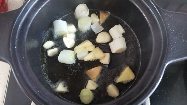 鱼头豆腐煲,砂锅里加入适量的油,下入葱姜蒜,爆香