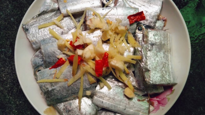 清蒸带鱼,带鱼腌制好后汁倒出,鱼面撒入姜丝,蒜碎,辣椒段