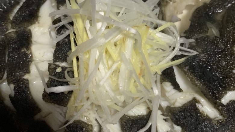 清蒸多宝鱼,上面铺上姜丝和葱丝,淋上酱油。