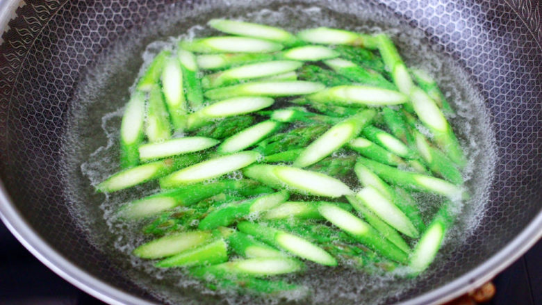 芦笋香干青口小炒,锅里烧开水,加入少量的盐,食用油,能保持蔬菜颜色不变,把切好的芦笋,倒入烧开的水里烫至变色断生的时候,捞出备用。