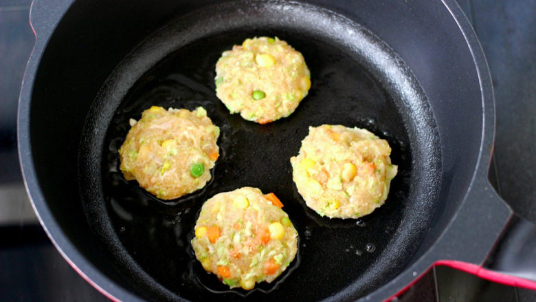 低脂低卡又好吃的鸡肉时蔬饼,热锅抹一层薄薄的食用油，把馅料分次等份，这些馅料我刚好做了9个，取一个摁扁放入锅中开始煎制。