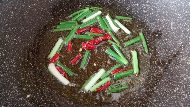 油焖春笋,炒锅内倒适量的食用油烧热,下入葱段和干红辣椒炒香。