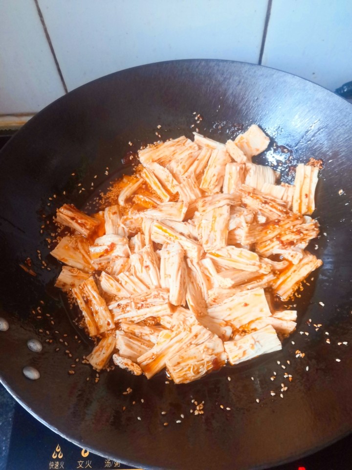 自制辣条(超简单,以后再也不用买辣条了),倒入煮好的腐竹,倒上麻椒油,翻拌均匀