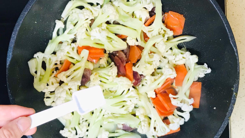 腊肉炒花菜,撒入盐调味,继续翻炒