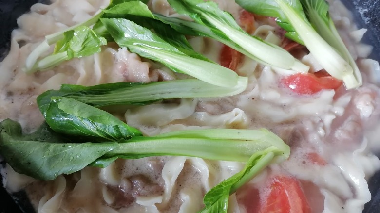 番茄牛肉面,煮一会沸腾之后加几次冷水,将青菜放入锅内