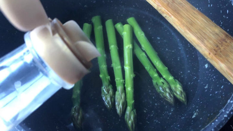 培根芦笋卷,烧开水后放入芦笋,倒入油。