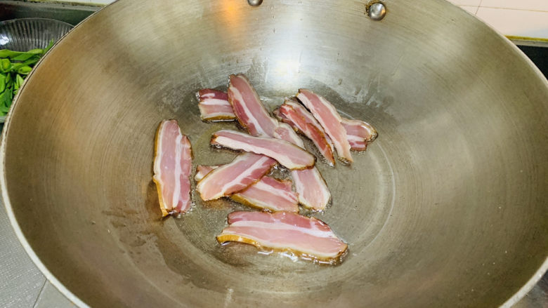 腊肉炒花菜,热锅下油,放入腊肉炒香。