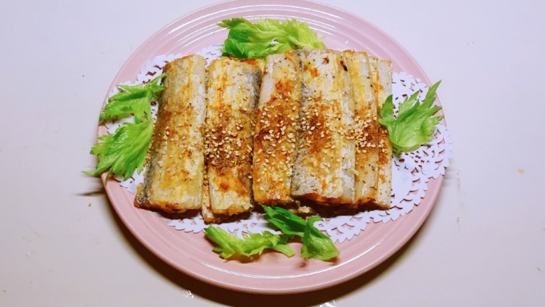 干煎带鱼,装盘,用芹菜叶装饰。