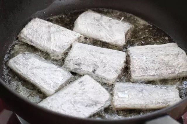 干煎带鱼,平底锅中倒适量食用油烧热,依次放入带鱼段用小火煎制,先不要着急翻动,等带鱼一面定型变色后再翻到另外一面。