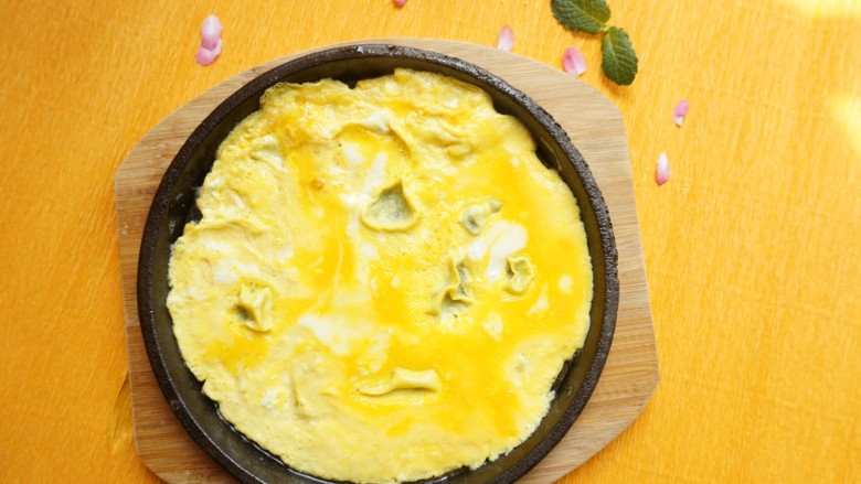 孜然肉片,同时铁板锅中加入两个鸡蛋液,小火煎成型