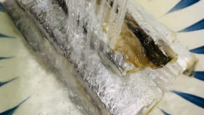 干煎带鱼,用水边冲带鱼,边去除内脏,洗干净