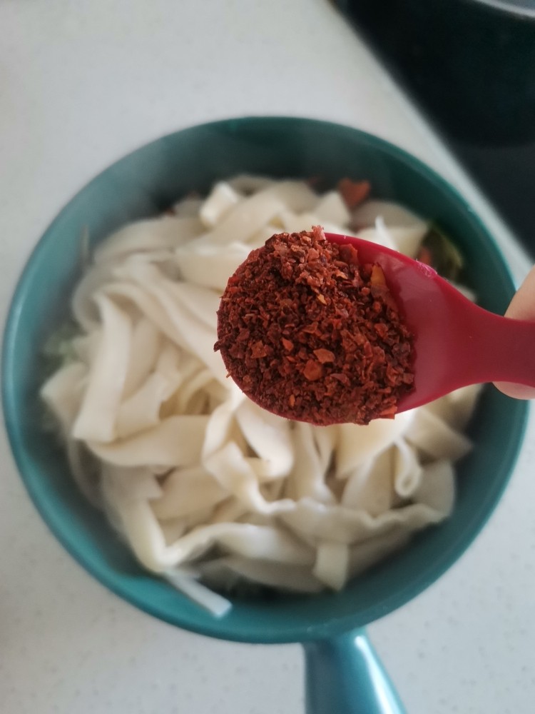 青菜凉拌手擀面,煮熟过冷水后捞到装调料和青菜的碗中,再加一勺干辣椒面