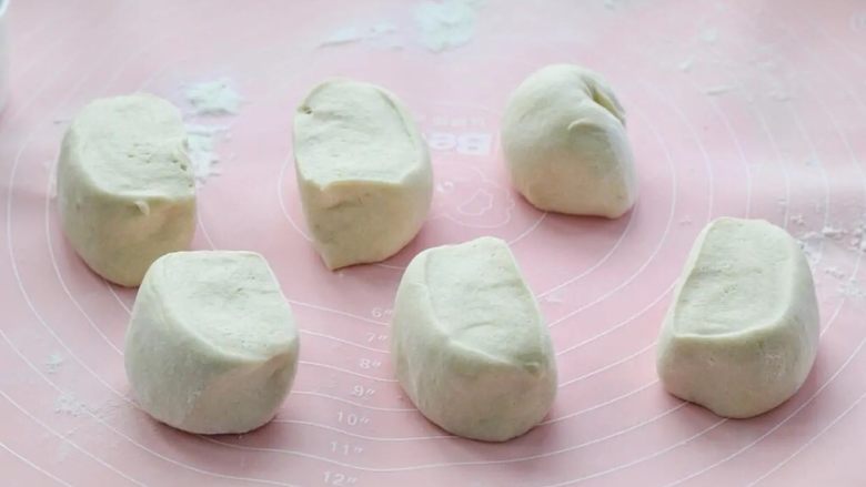 玉米馒头,操作台上撒适量干面粉防粘,取出面团充分揉匀,这一步要将面团里面的空气充分揉出来,然后分成均匀的六个小面团。