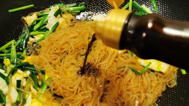 韭菜炒粉丝,放入拌好的粉丝,再加入一汤匙酱油,。
