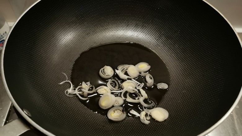 韭菜炒香干,起油锅放入食用油,放入葱片炒香。