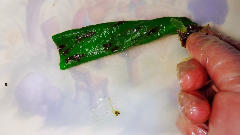 擂椒皮蛋,煎好的尖椒放凉,剥去煎出的一层皮。
