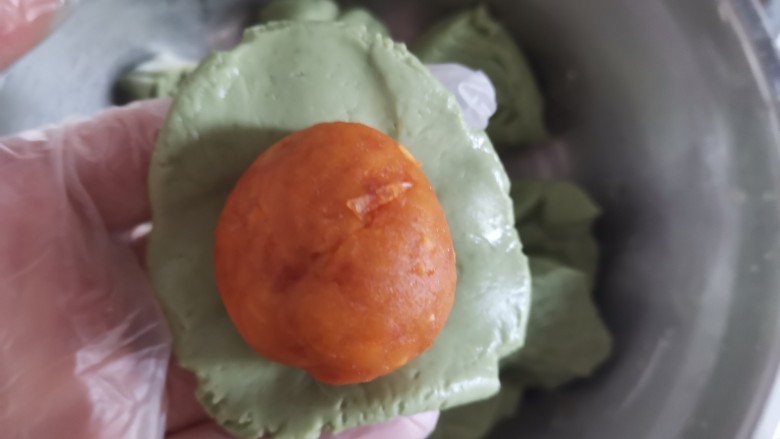 艾草青团,取一个剂子揉圆压成饼状,包入馅料