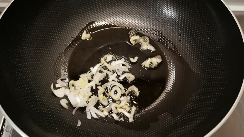 香椿炒腊肉,起油锅放入食用油,油热后放入葱片炒香。