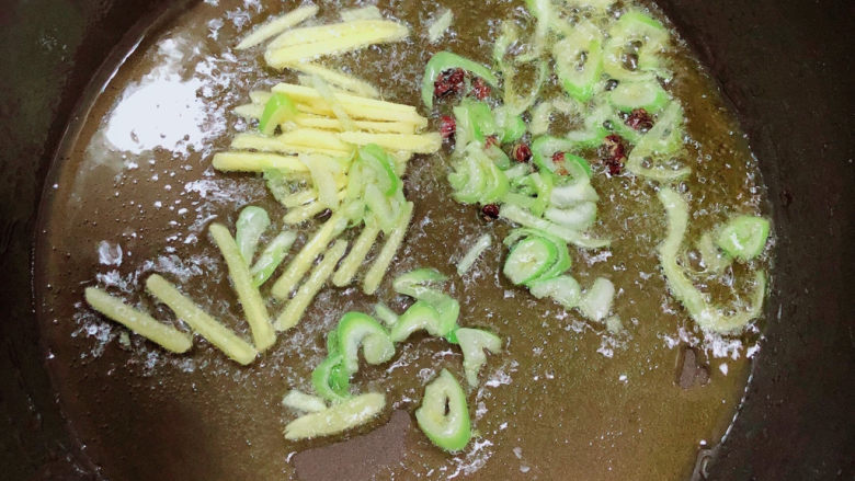 蒜苔回锅肉,锅中倒入油,加热至五成热,放入<a style='color:red;display:inline-block;' href='/shicai/ 134659'>花椒粒</a>、葱姜爆香。