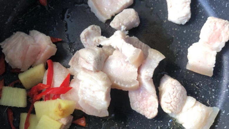 蒜苔回锅肉,下入尖椒、生姜和肉片,翻炒均匀出香味。