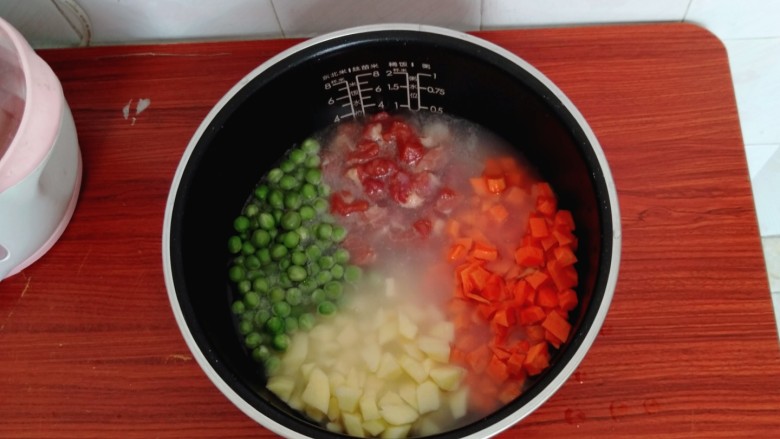 懒人焖饭,把准备好的豌豆,胡萝卜丁,土豆丁,肉丁摆放在大米上面