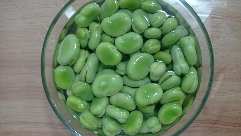 雪菜炒蚕豆,放入碗中，用水浸泡放入一小勺盐