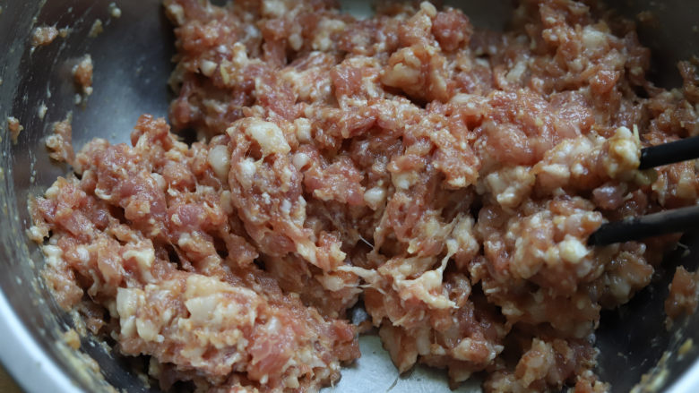槐花饺子,然后就用筷子,两根四根都可以,往同一个方向快速搅拌,搅拌到汤汁完全被肉馅吸收,此时的肉馅看起来很黏稠。