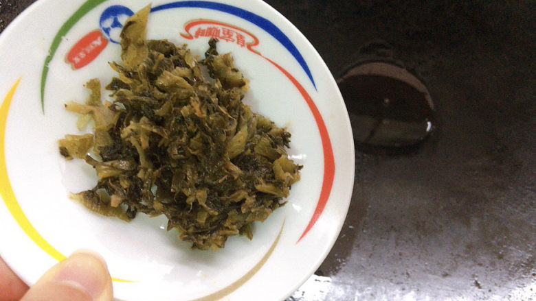 雪菜炒蚕豆,锅烧热油,加入腌制好的雪菜煸炒出香味