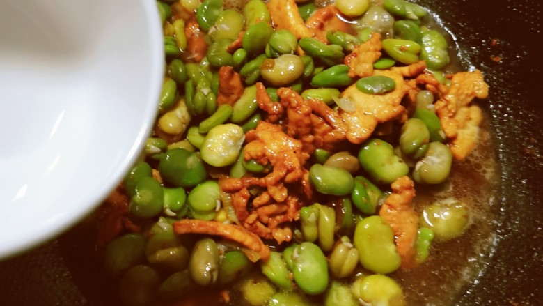 韭菜炒蚕豆,倒入30克清水,烧开。