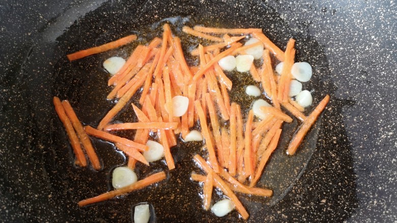 金针菇炒鸡蛋,锅里继续倒油烧热,下入蒜片炒香,下入胡萝卜丝翻炒均匀。