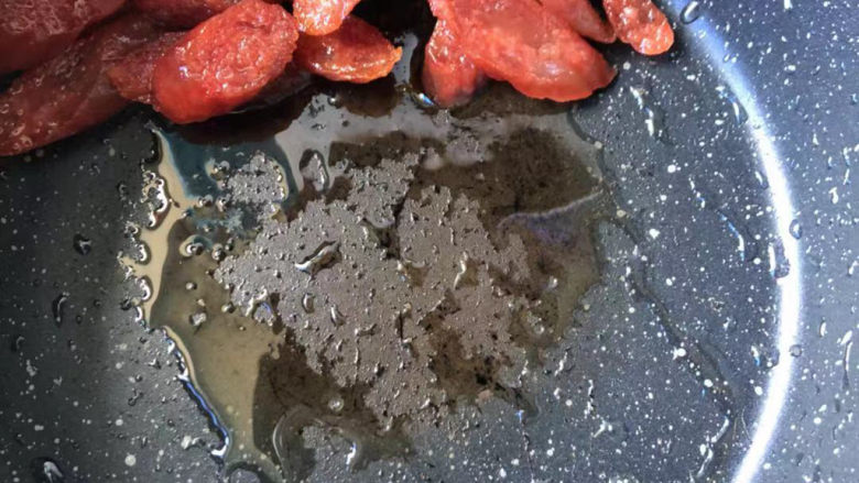 西葫芦炒腊肠,把腊肠推到锅的一侧,余油滤出来。