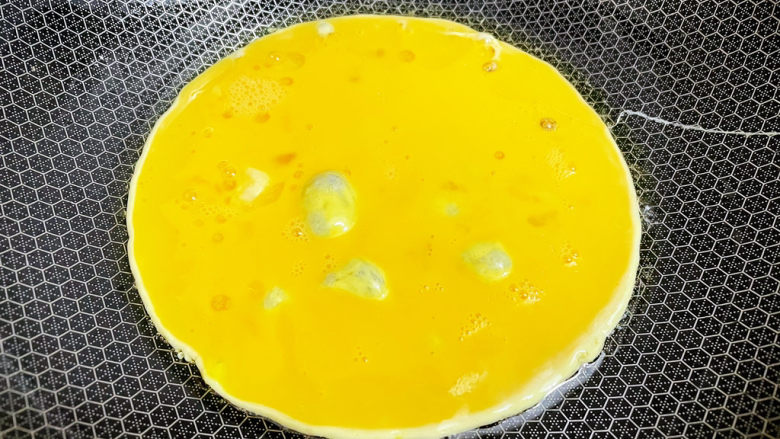 金针菇炒鸡蛋,锅中倒入适量的食用油烧热,倒入蛋液,煎至定型后铲碎